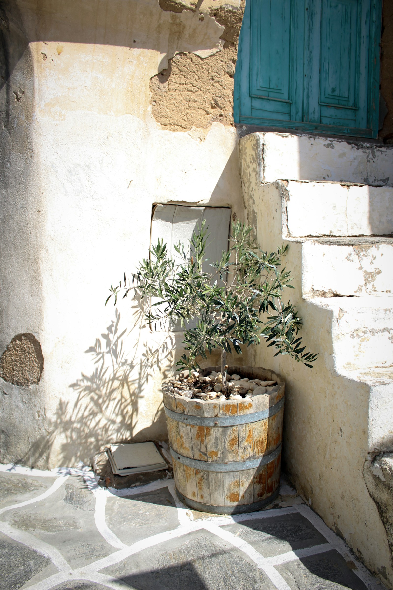 Traditional Greek home with weathered walls, stone steps and a blue wooden door