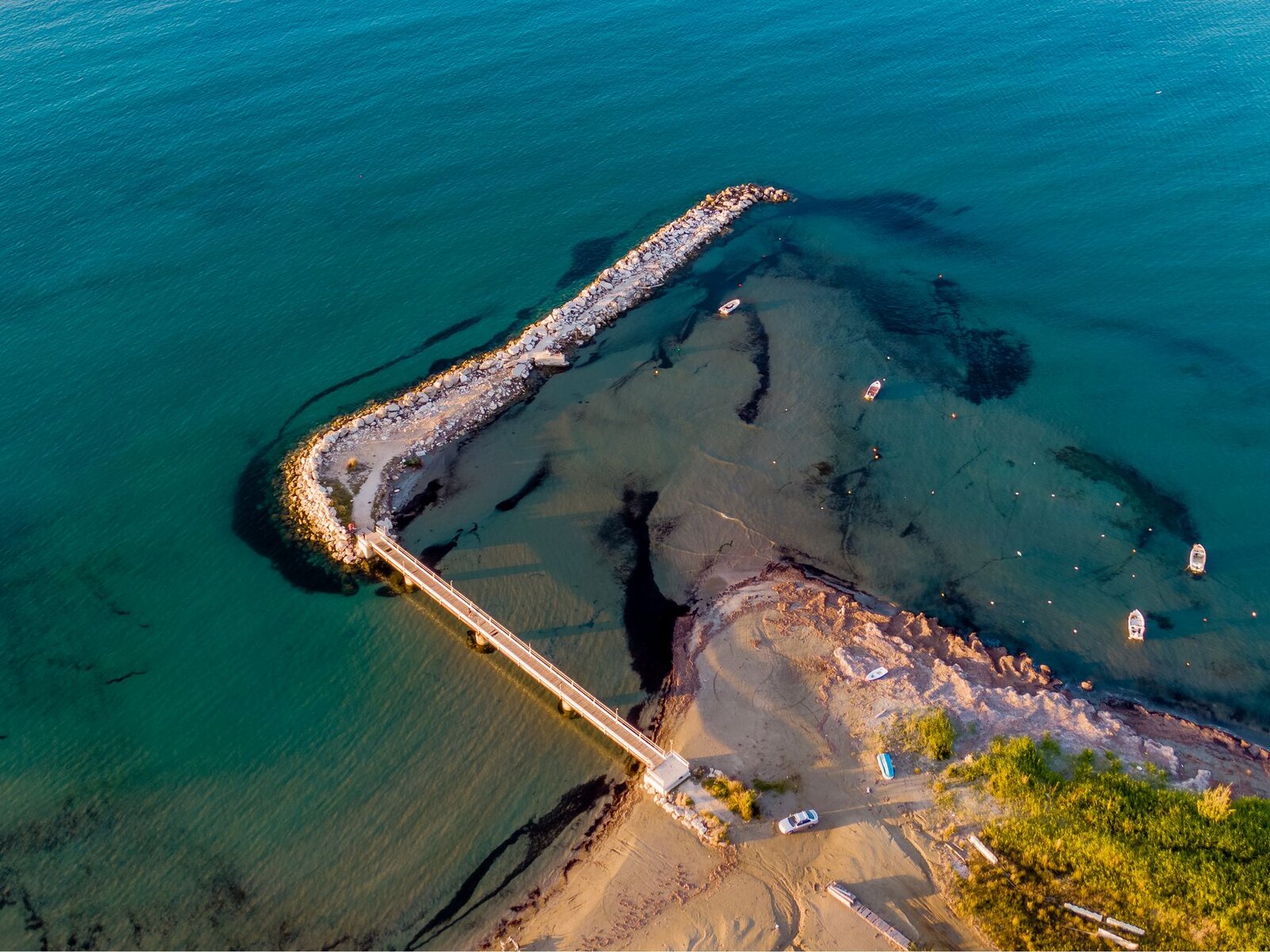 Aerial view of clear Ionian water and a small pier on Corfu's coast