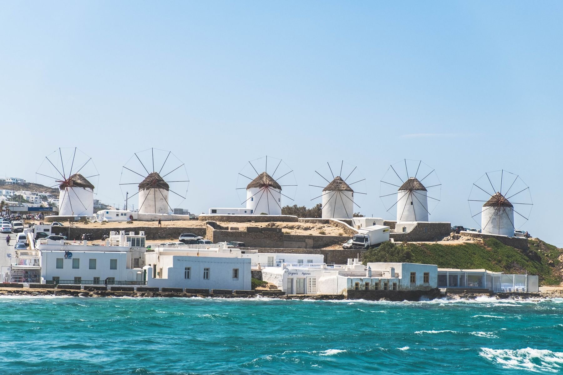 Traditional Mykonos windmills above whitewashed buildings beside the Aegean
